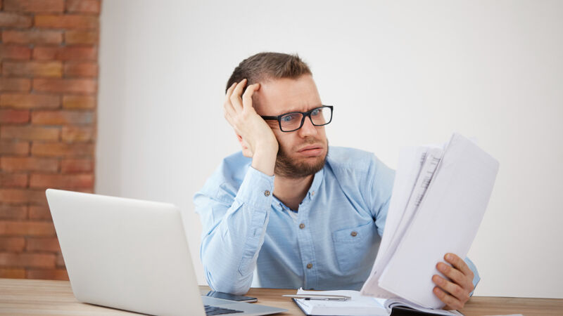 Unhappy man sitting in office looking at documents