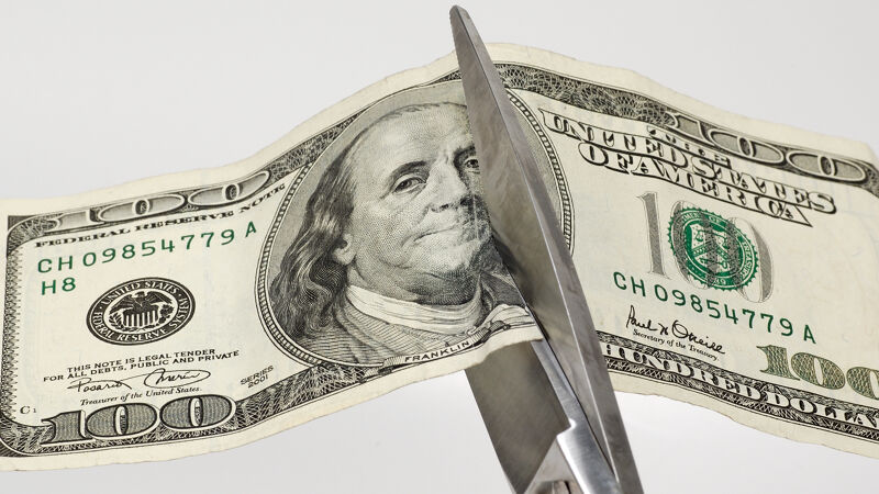 Scissors cutting a $100 bill (US dollars, of course) in two